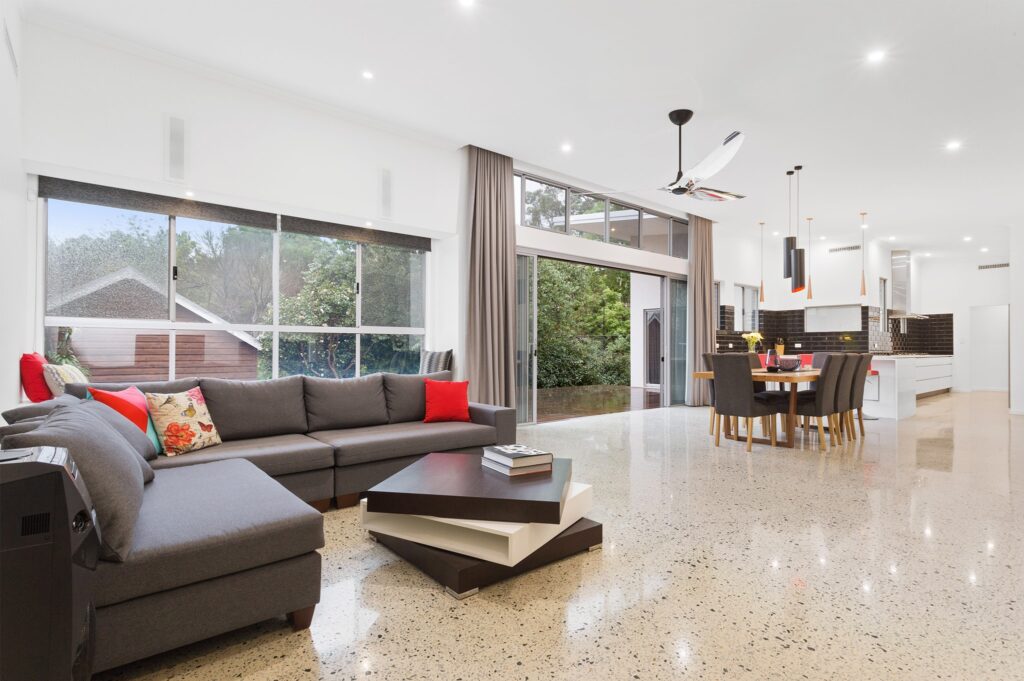 Open plan dining, living, kitchen area with a polished white concrete floor