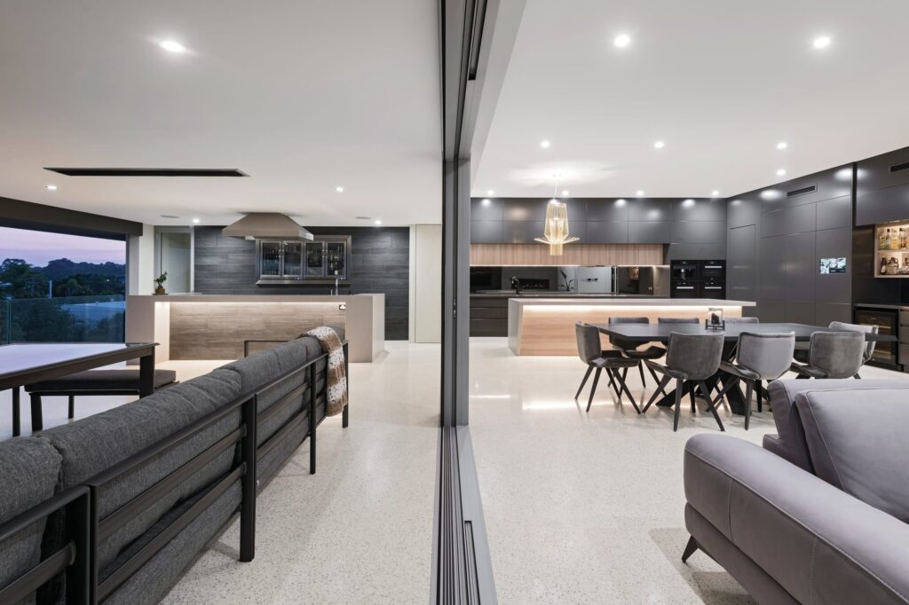 Open plan living area leading into a balcony and bar with polished white concrete floors